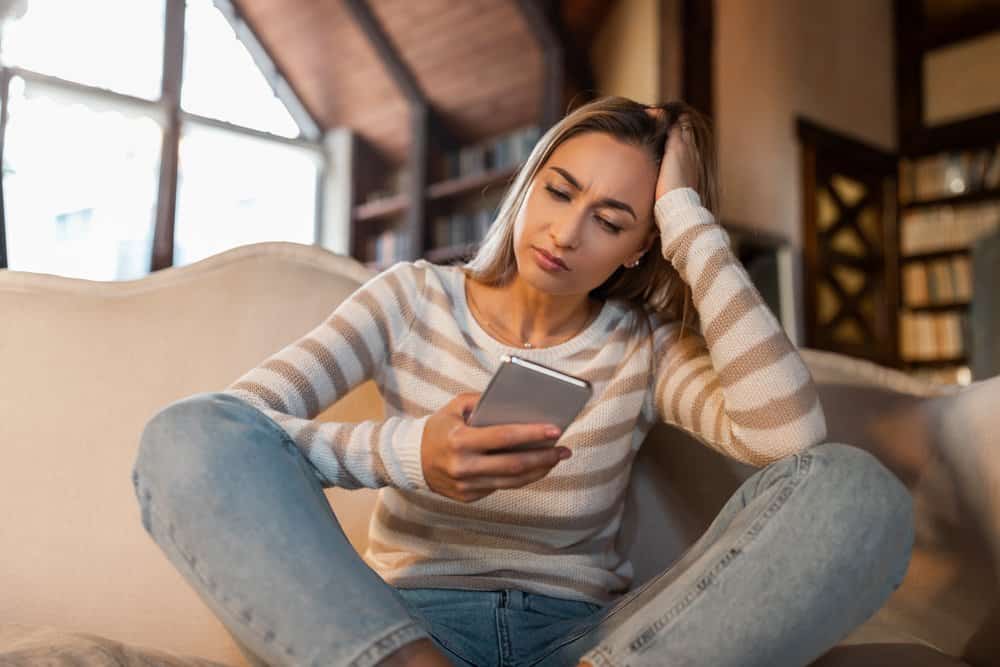 A woman sits reading I'm sorry messages for a girlfriend sent to her