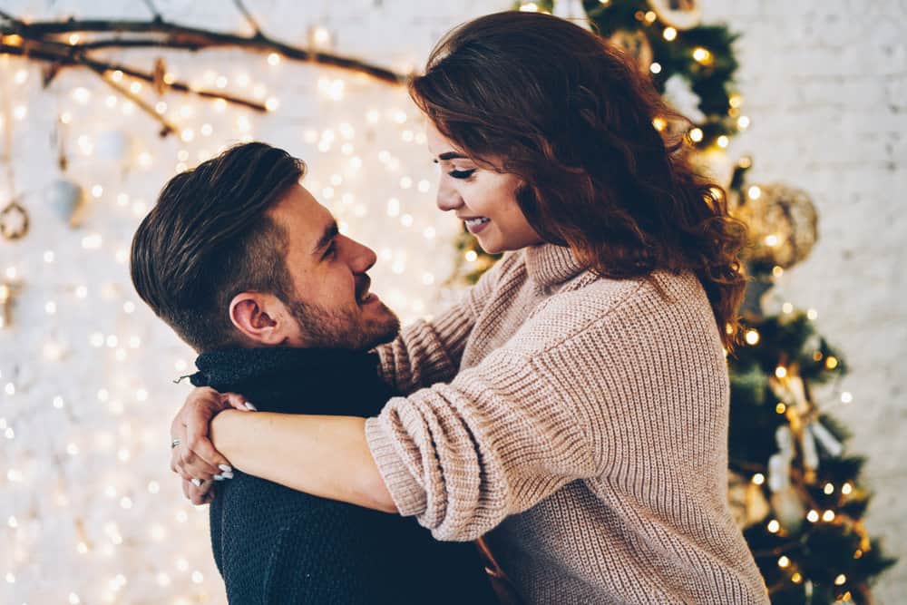 A couple embrace after she reads romantic Christmas messages for her