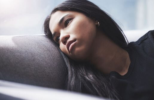 A woman lies asleep on a couch, exhibiting the characteristics of a broken person.