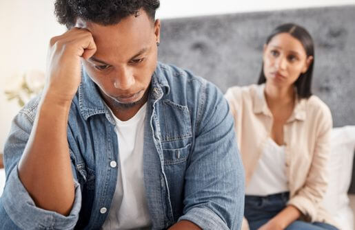 A man and woman sit on a bed, engrossed in their phones. This image depicts characteristics of a broken person, lost in technology and disengaged.
