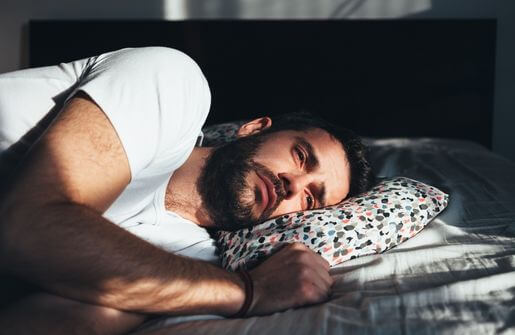 The image depicts a man in a state of slumber on a bed, with a hint of melancholy as he reminisces about his ex-wife