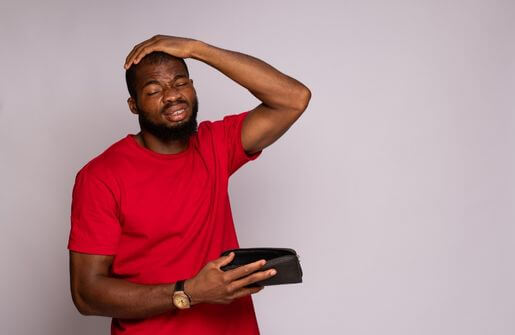 A man examines a wallet, possibly contemplating financial difficulties or the symbolic meaning of being broke.