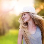 A stylish woman in a hat and long hair strolls through the park, enjoying the prime of her life.