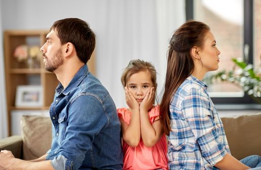 A family, with their hands on their faces, sits on the couch. The image depicts a situation where the ex-partner wants to reconcile
